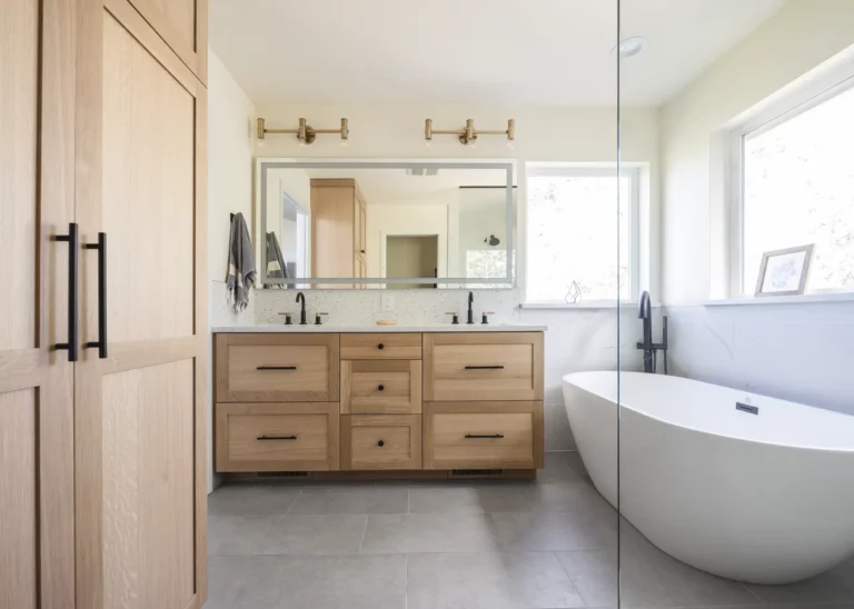 Modern bathroom in Bend, Oregon with wooden cabinets, double sink vanity, large mirror, freestanding tub, and a glass shower enclosure beautifully executed by a general contractor specializing in bathroom remodels.